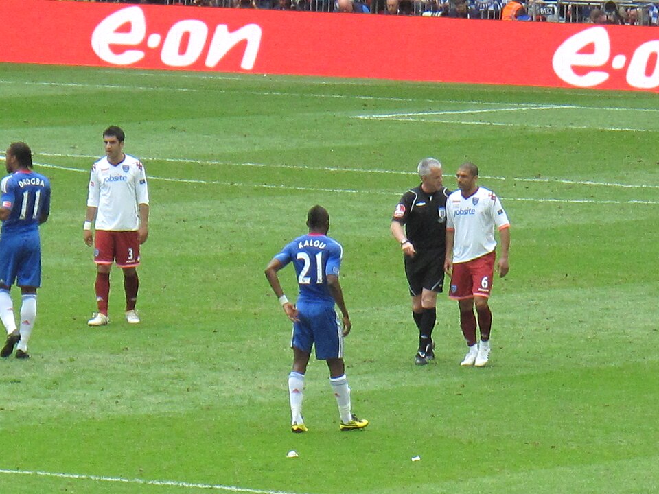 Referee Chris Foy speaking with Hayden Mullins during the final, with other players nearby